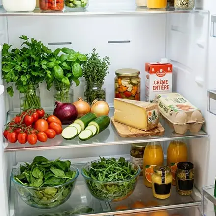 Un frigo ouvert : tomates, herbes, courgettes, fromage, œufs.